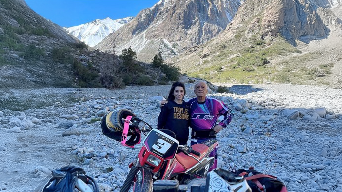 Rodolfo posing for a picture in front of mountain scenery with his bike.