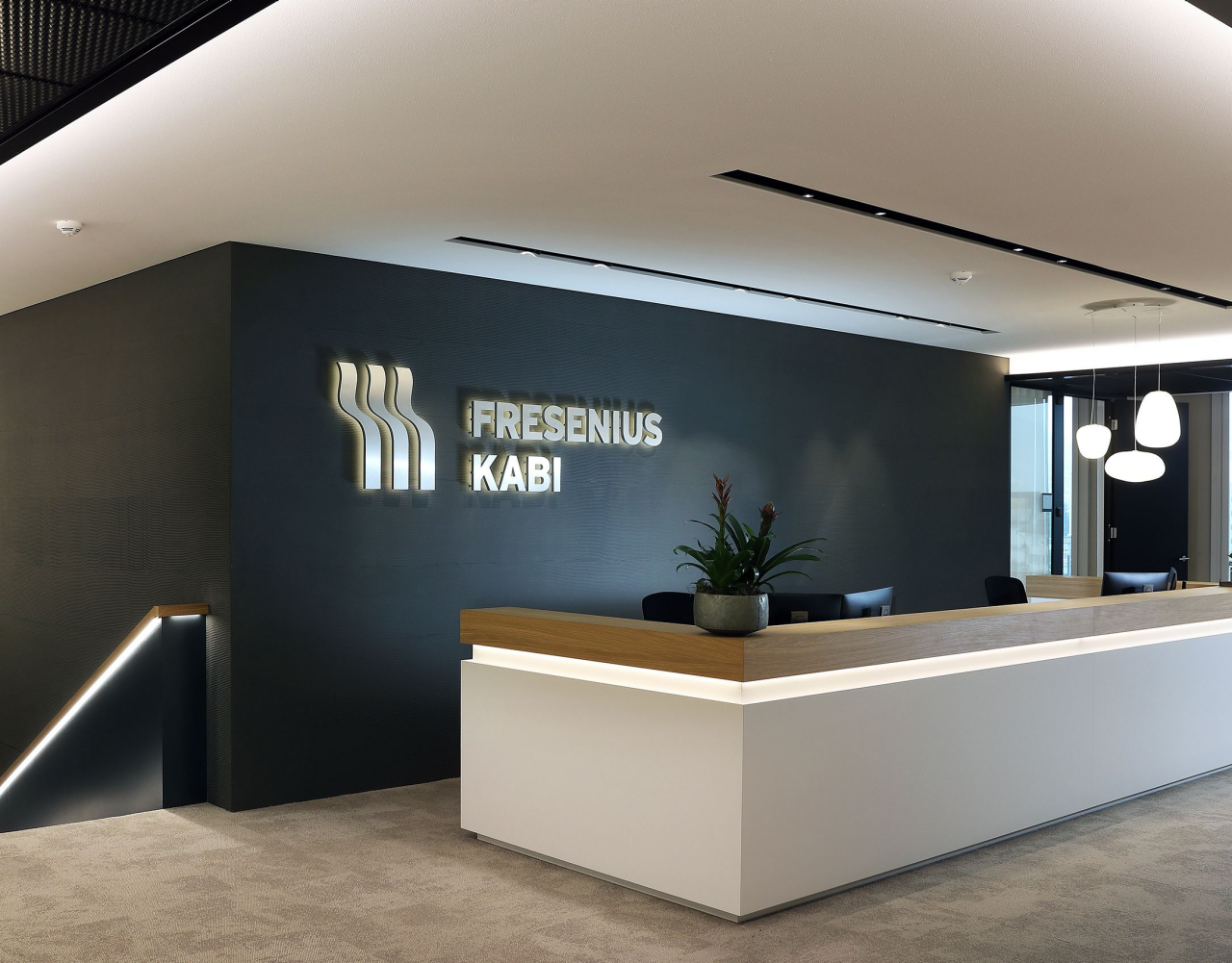"Rezeption im modernen Büro von Fresenius Kabi mit Firmenlogo an der Wand und Empfangstresen im Vordergrund